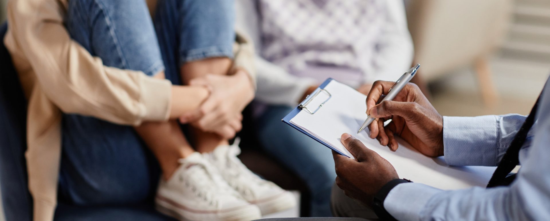 Close up of African-American psychologist taking notes on clipboard in therapy session for children